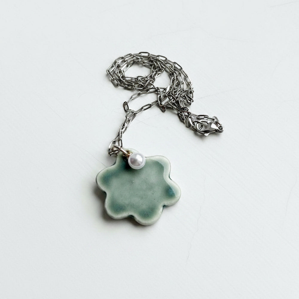 Necklace with a green ceramic pendant and pearl on a white background