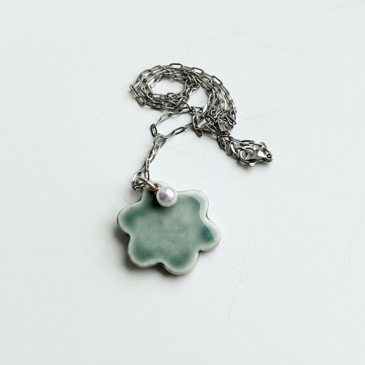 Necklace with a green ceramic pendant and pearl on a white background