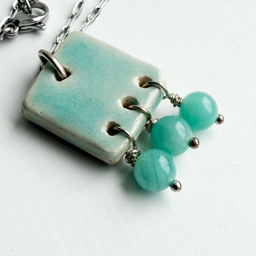 Necklace with a turquoise pendant and beads on a white background