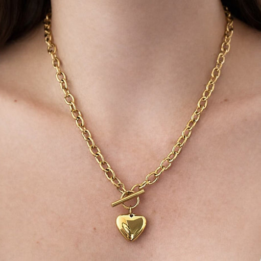 Gold chain necklace with a heart pendant on a person's neck