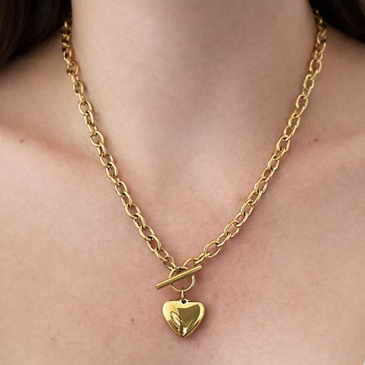 Gold chain necklace with a heart pendant on a person&