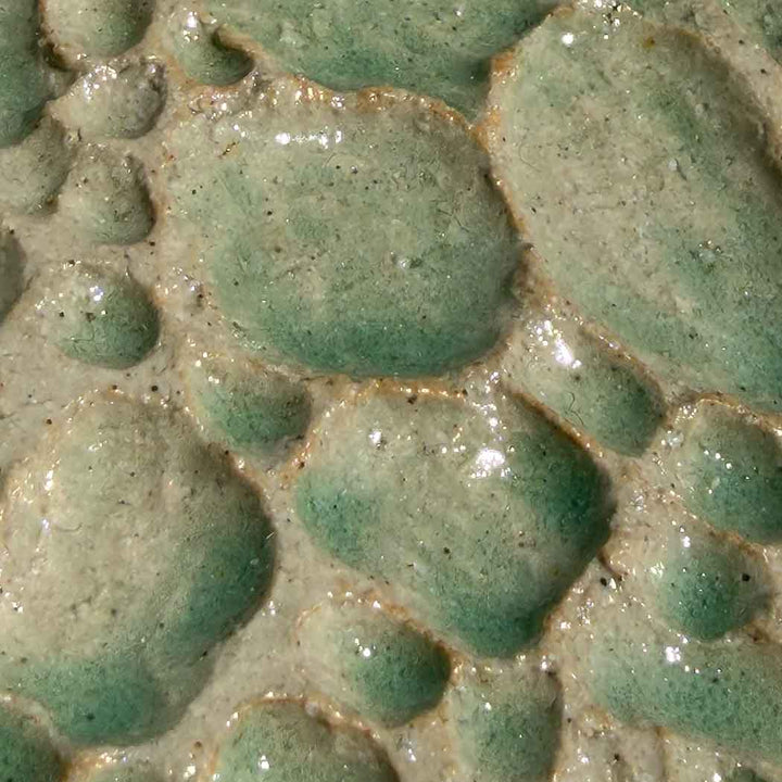 Close-up of textured green ceramic surface with raised patterns