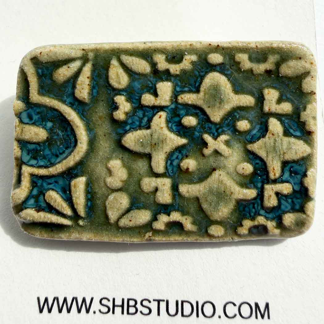 Brooch ceramic tile with pattern design on a white background, featuring the SHB Studio logo.