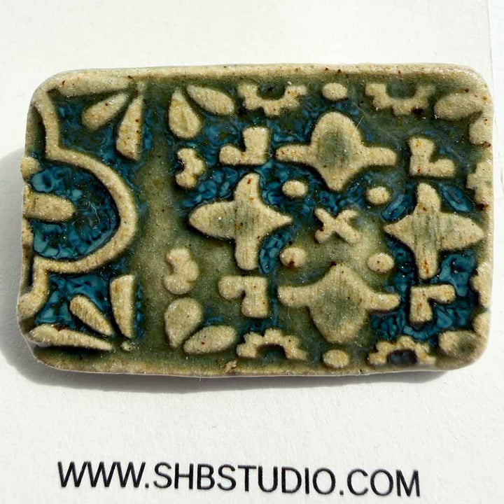 Brooch ceramic tile with pattern design on a white background, featuring the SHB Studio logo.