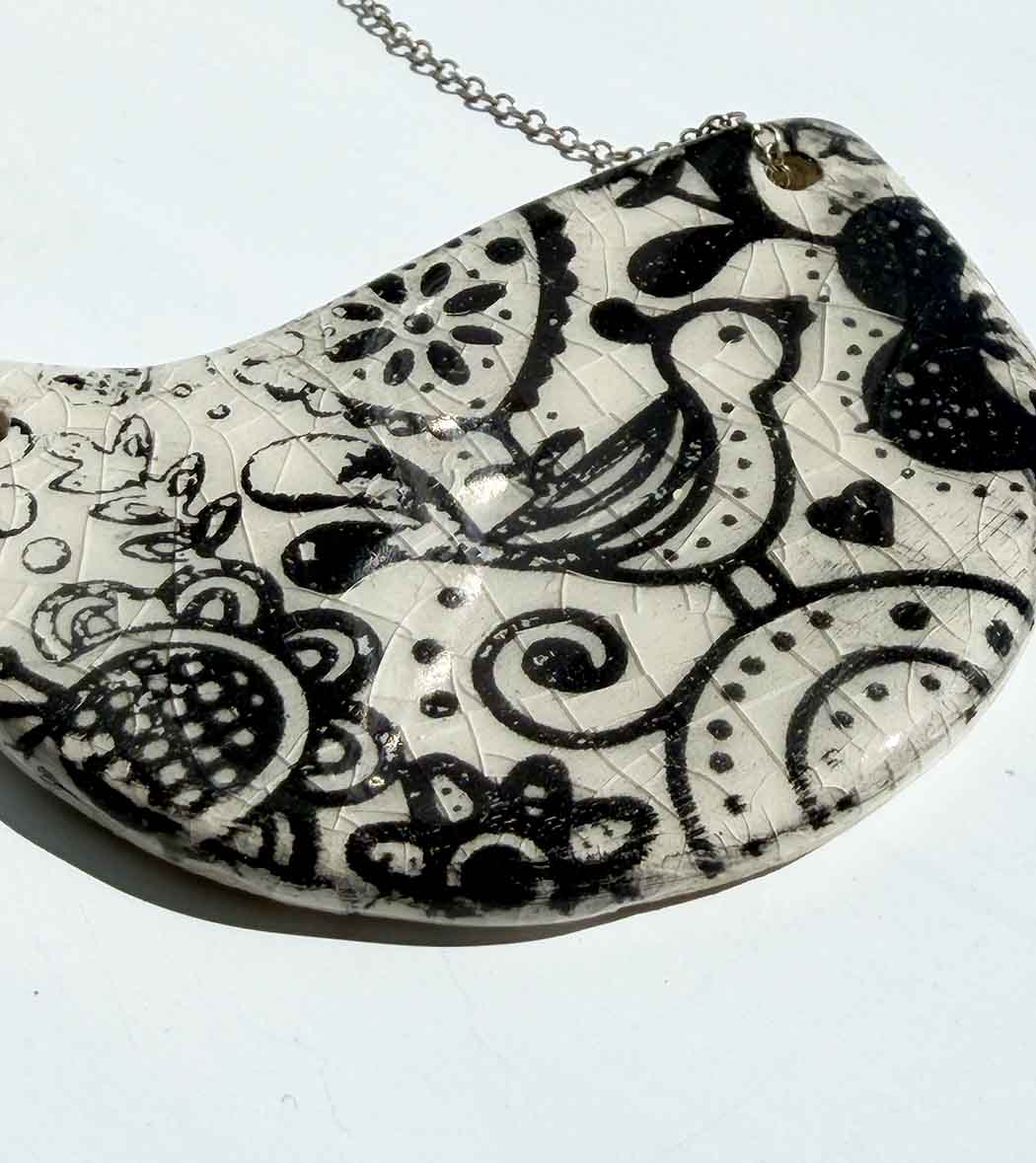 Black and white patterned ceramic necklace shows bird and flower motif