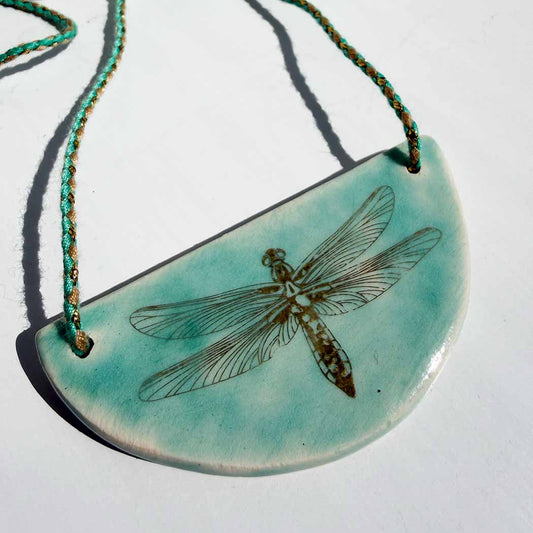 Turquoise necklace with a dragonfly design on a white background