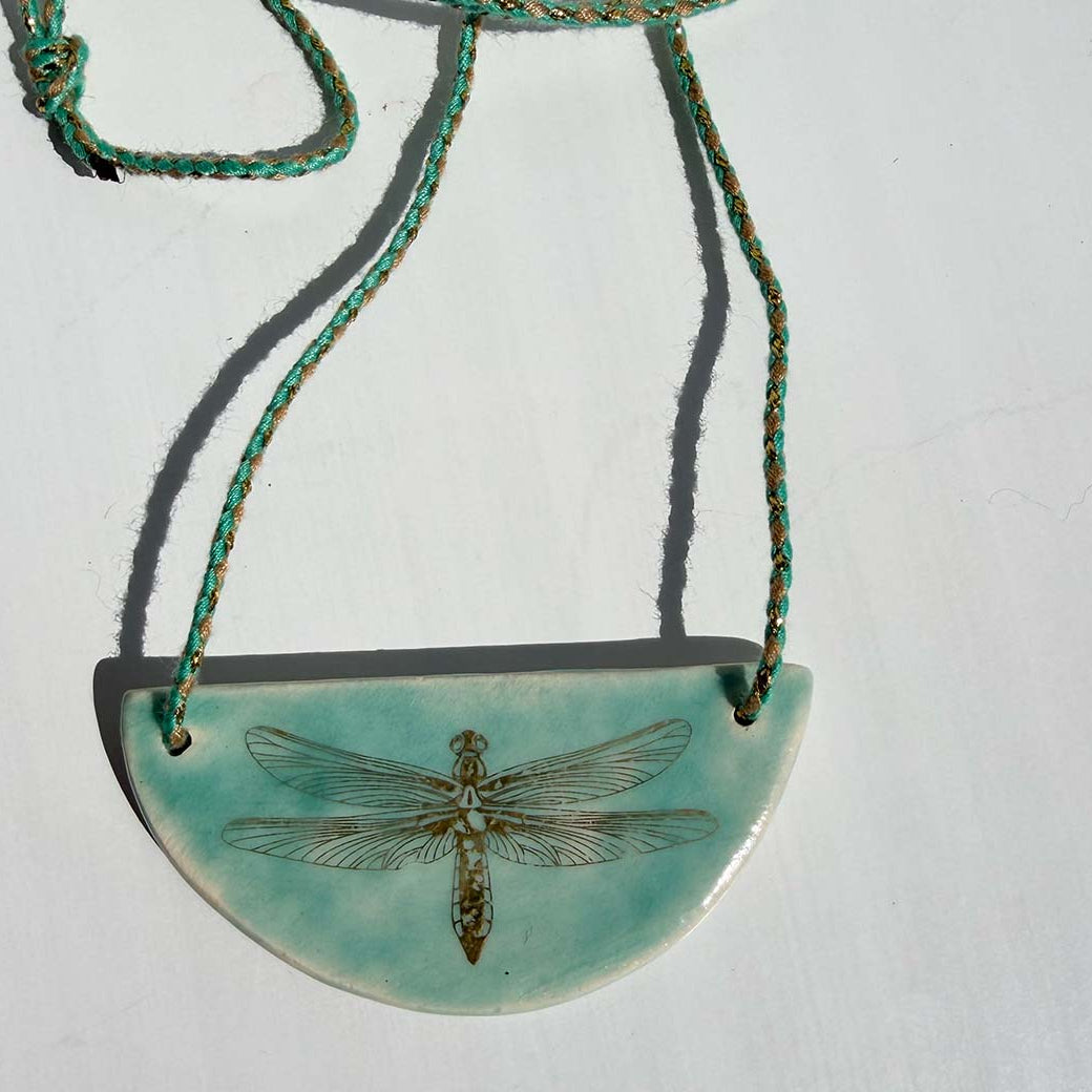 Necklace with a turquoise pendant featuring a dragonfly design on a white background