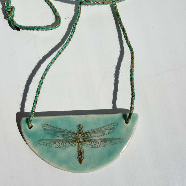 Necklace with a turquoise pendant featuring a dragonfly design on a white background
