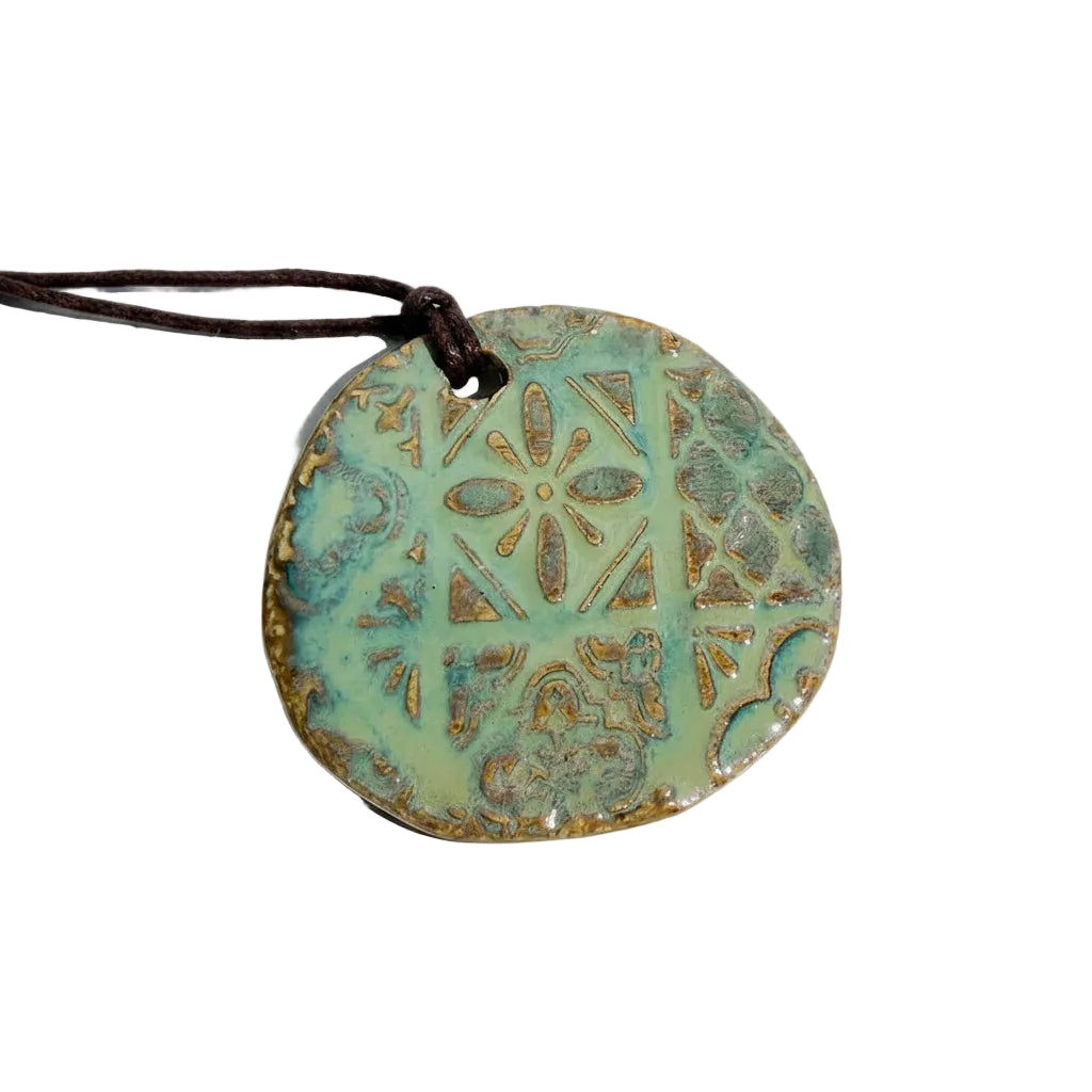 Round ceramic pendant with decorative patterns on a white background