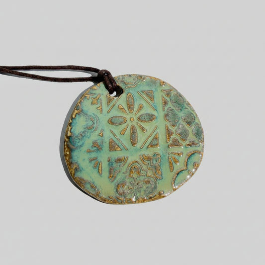 Round ceramic pendant with decorative patterns on a white background