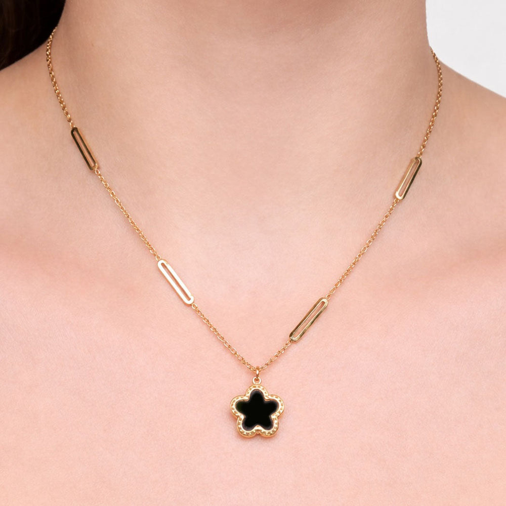 gold necklace with a black pendant on a plain background