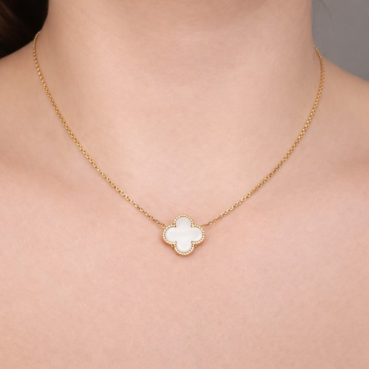 Gold necklace with a clover-shaped pendant on a person&