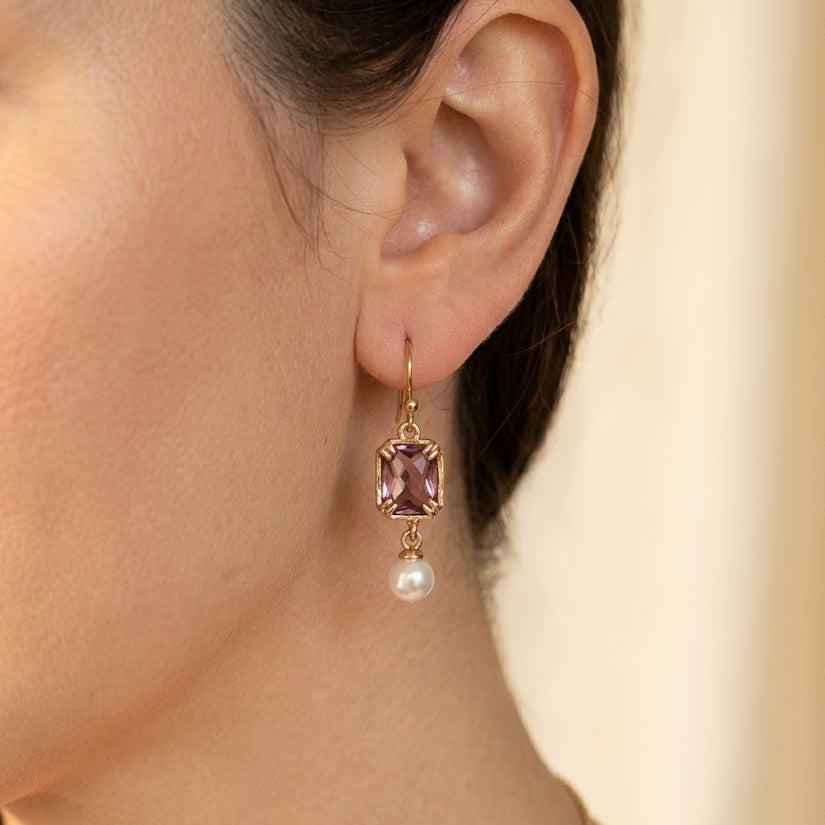 Woman wearing a light purple crystal glass and pearl drop earring in an 18K gold-plated square setting