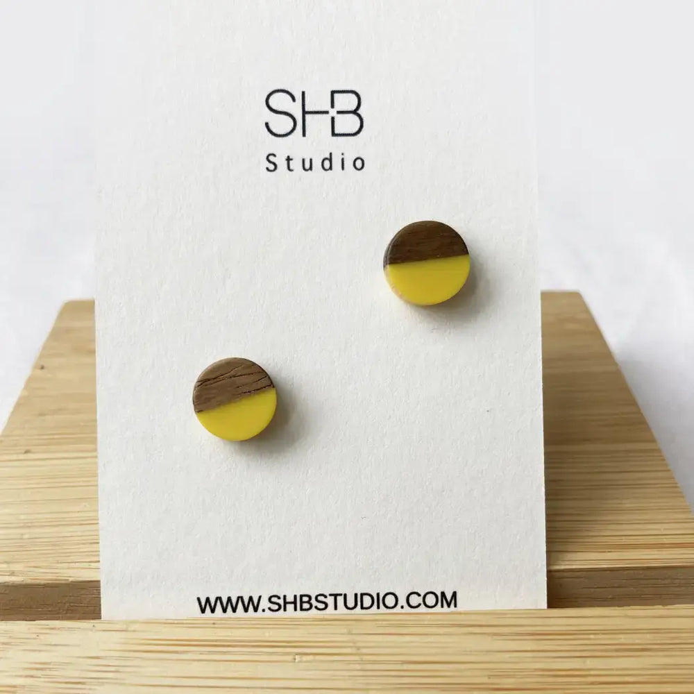 Wooden earrings with yellow and brown design on a white card with SHB Studio branding.