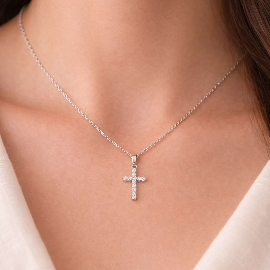 Silver cross necklace on a person wearing a white top
