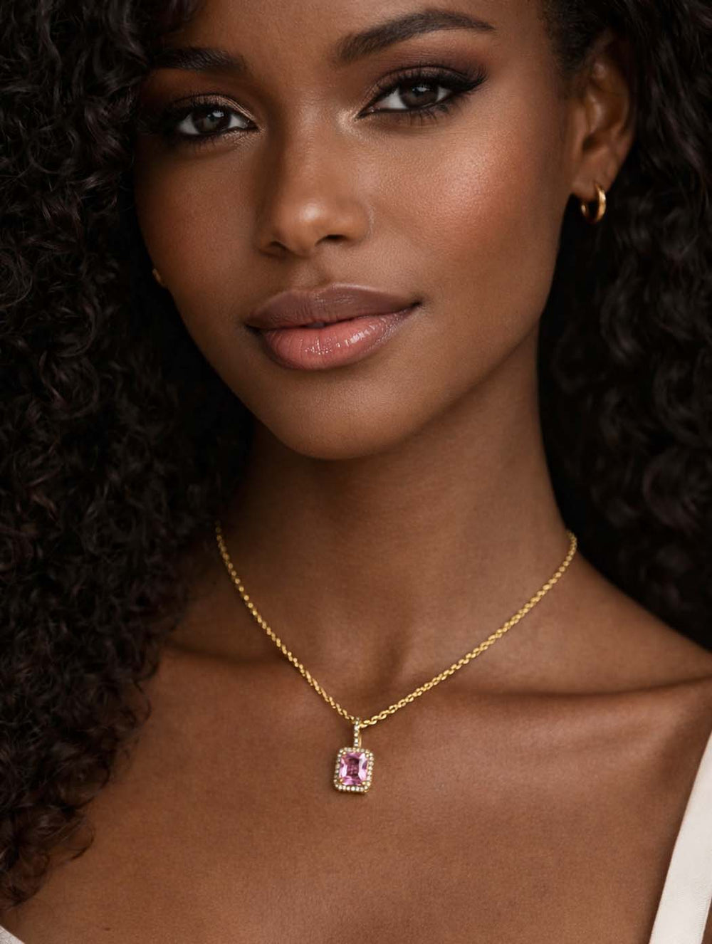Woman wearing 18K gold plated stainless steel necklace with pink square zircon pendant and delicate gold chain.