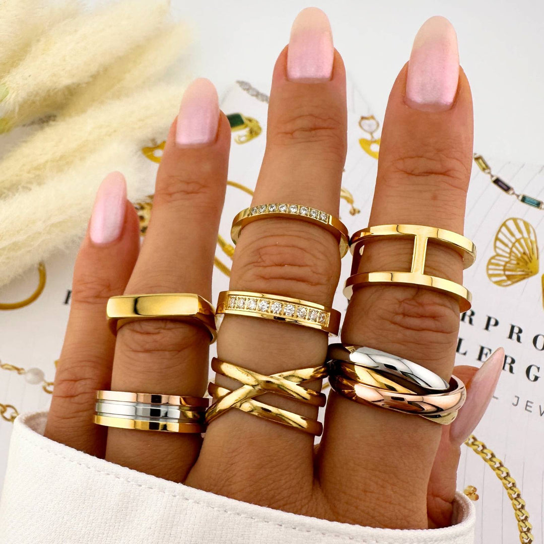 Close-up of fingers wearing multiple gold and rose gold rings on a blurred background