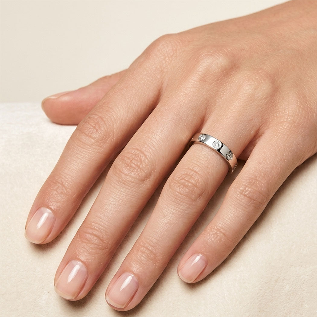 Hand  wearing ring silver with small zirconia on a beige background