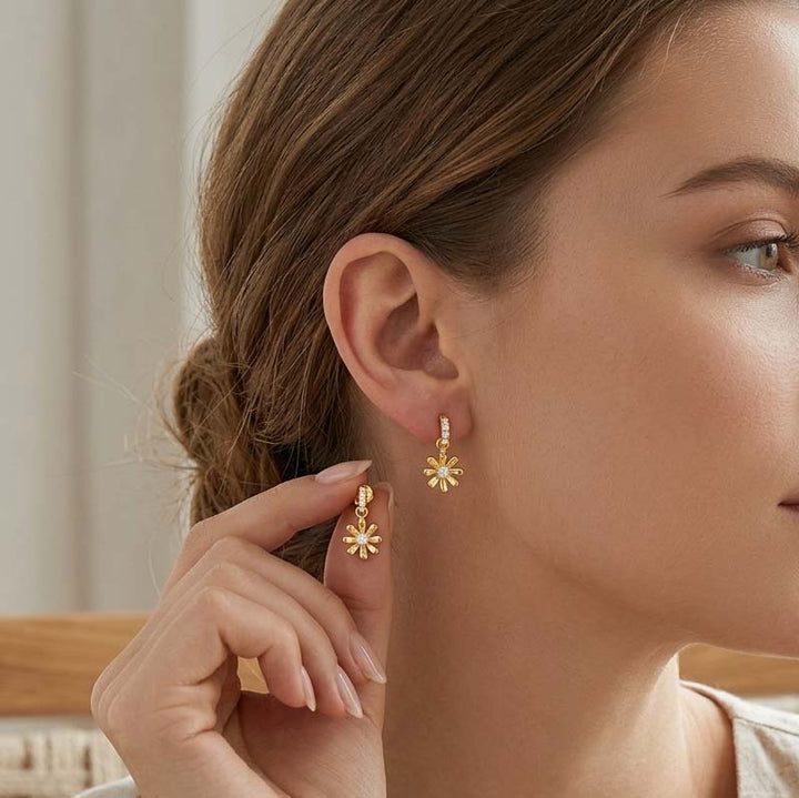 Woman wearing gold floral earrings with a neutral background