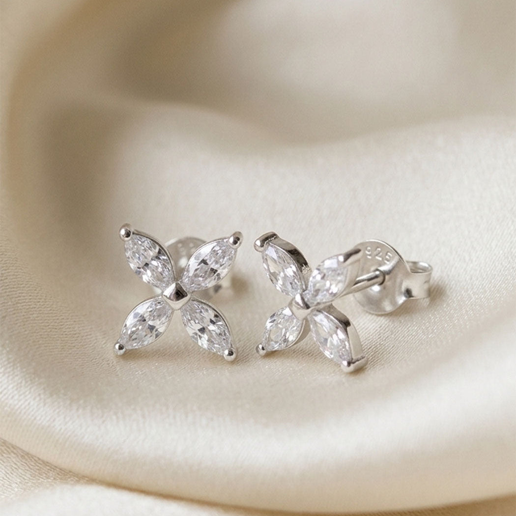 Butterfly-shaped silver earrings with clear zirconia on a beige fabric background