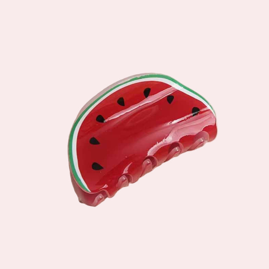 Watermelon-shaped hair claw on a beige surface background.