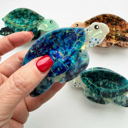 Hand holding a blue turtle-shaped object with other turtle-shaped objects in the background.