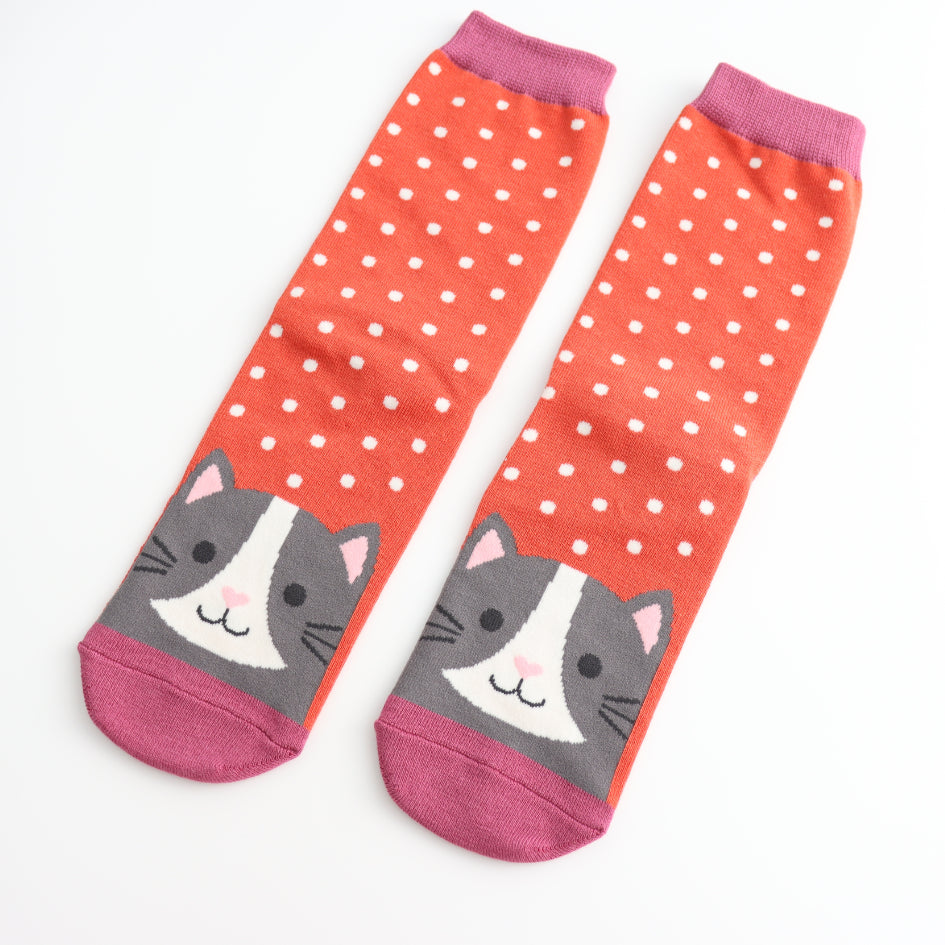 Cute burnt orange socks with white polka dots and a grey cat face design, fun animal-themed bamboo socks for women.