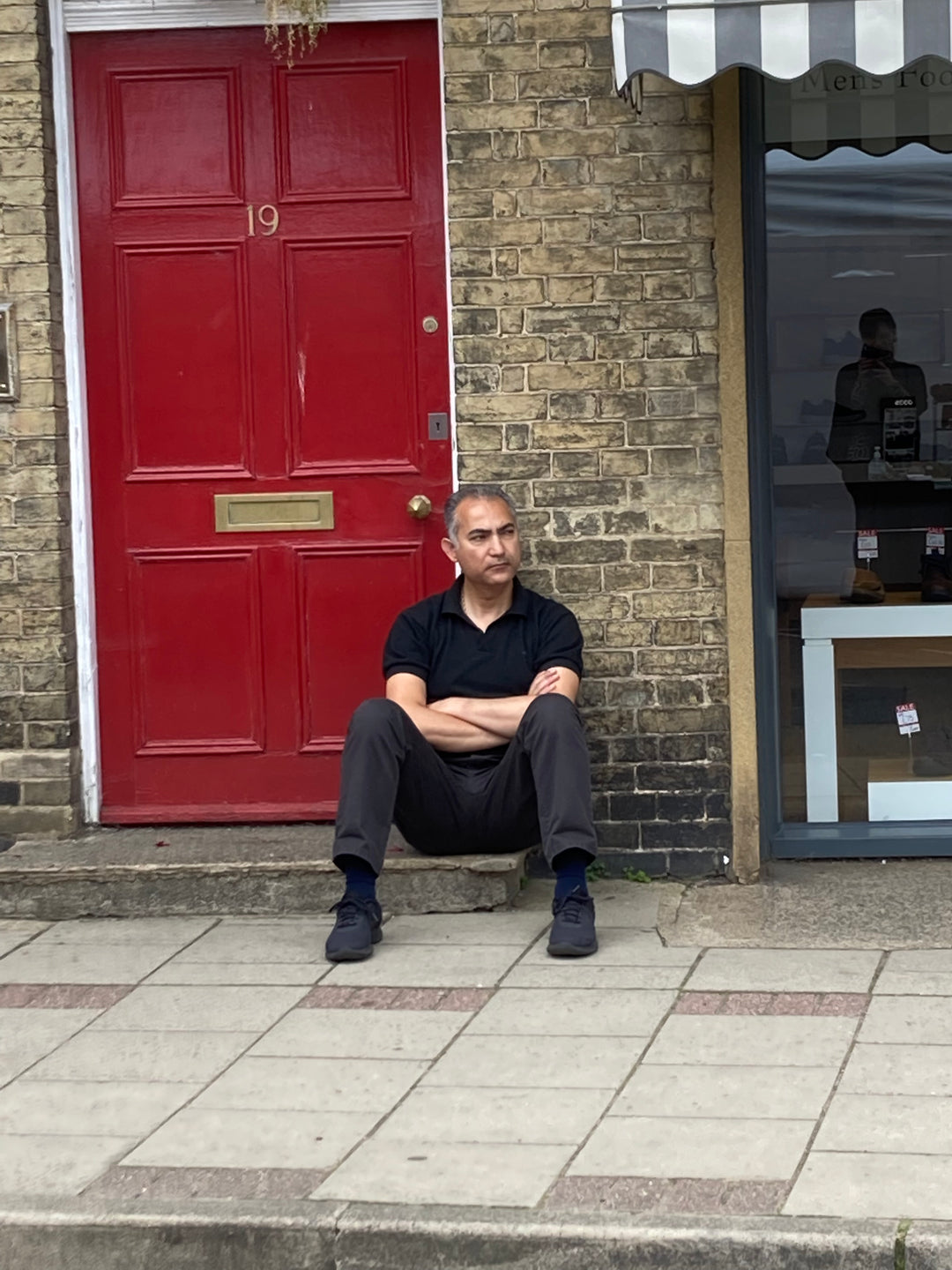 Person sitting outside red door